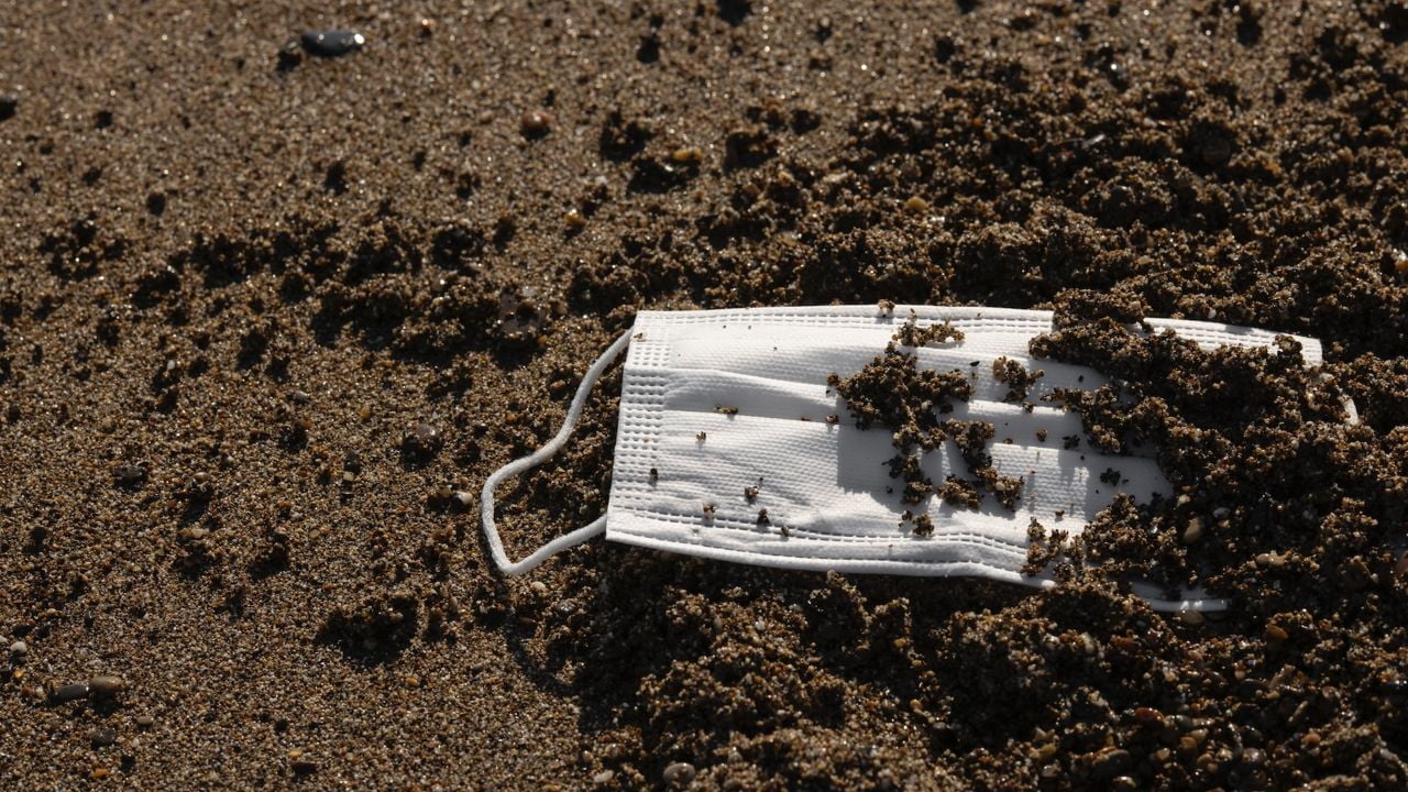 Ein Mund-Nasenschutz, der in einem Haufen Erde liegt.