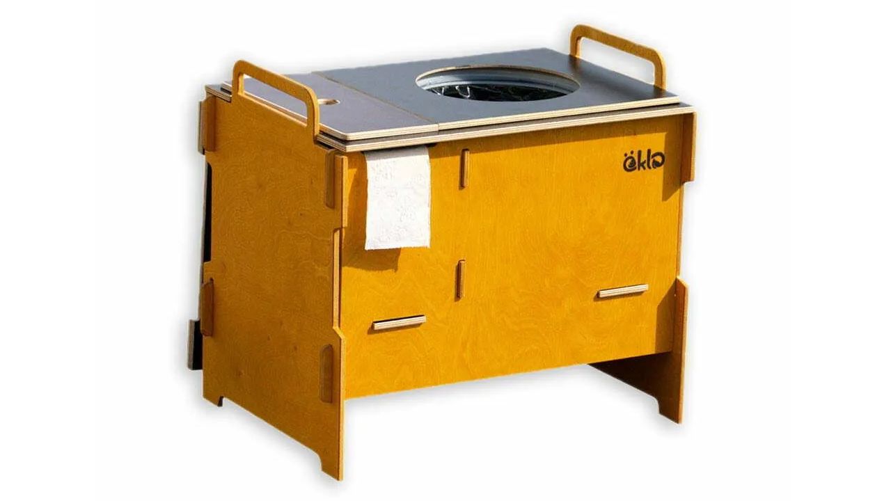 Eine öKlo-Campingtoilette auf weißem Hintergrund. Sie ist im klassischen öKlo-Braun lasiert und hat auf jeder Seite einen Griff für einfache Transportation.