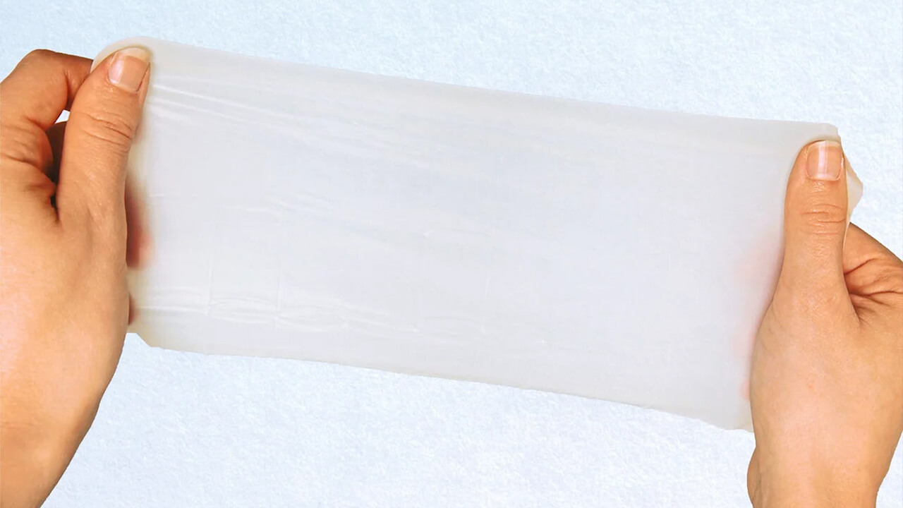 Zwei Hände halten ein transparentes, flexibles Lecktuch vor einem hellen Hintergrund.